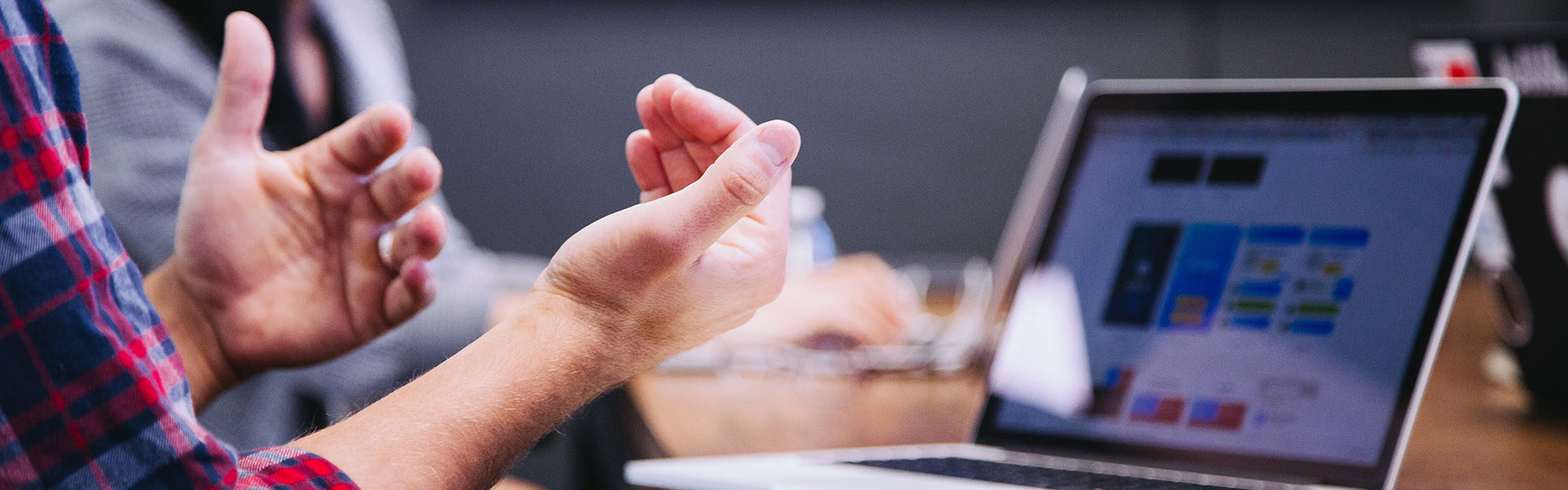Eine Person vor einem Laptop im Gespräch mit einer weiteren Person | Sprechen Sie mit uns: Bei GERDITEX bekommen Sie die Lösung, die Sie brauchen!